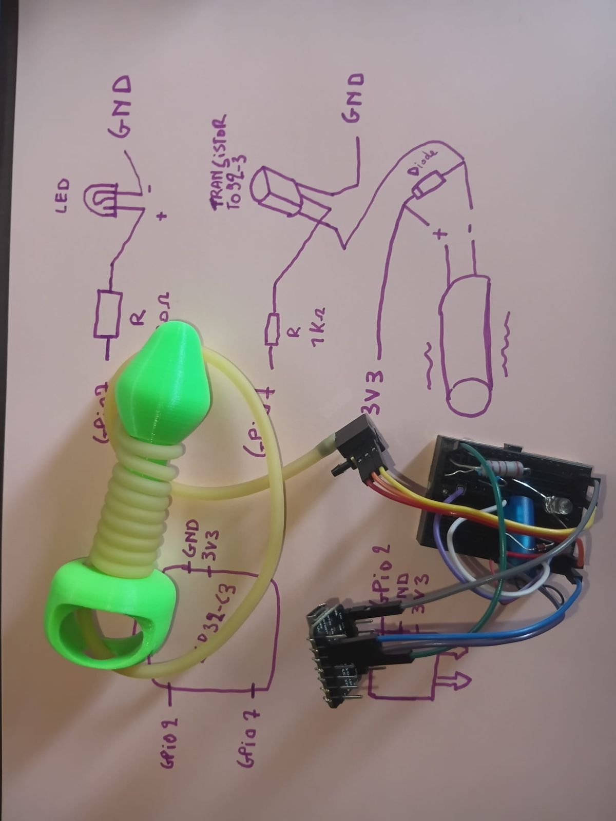 Green plug with yellow silicone tubing coiled around it, connected to a breadboard prototype with sensor, transistor, motor and LED.